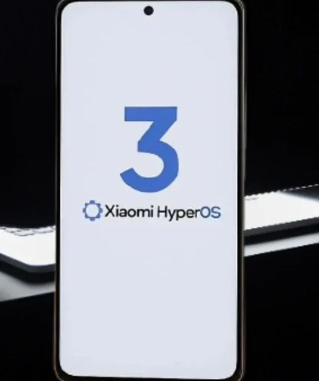Smartphone Xiaomi exibindo a logo "3 Xiaomi HyperOS" em tela branca, com um fundo escuro e detalhes de luz.