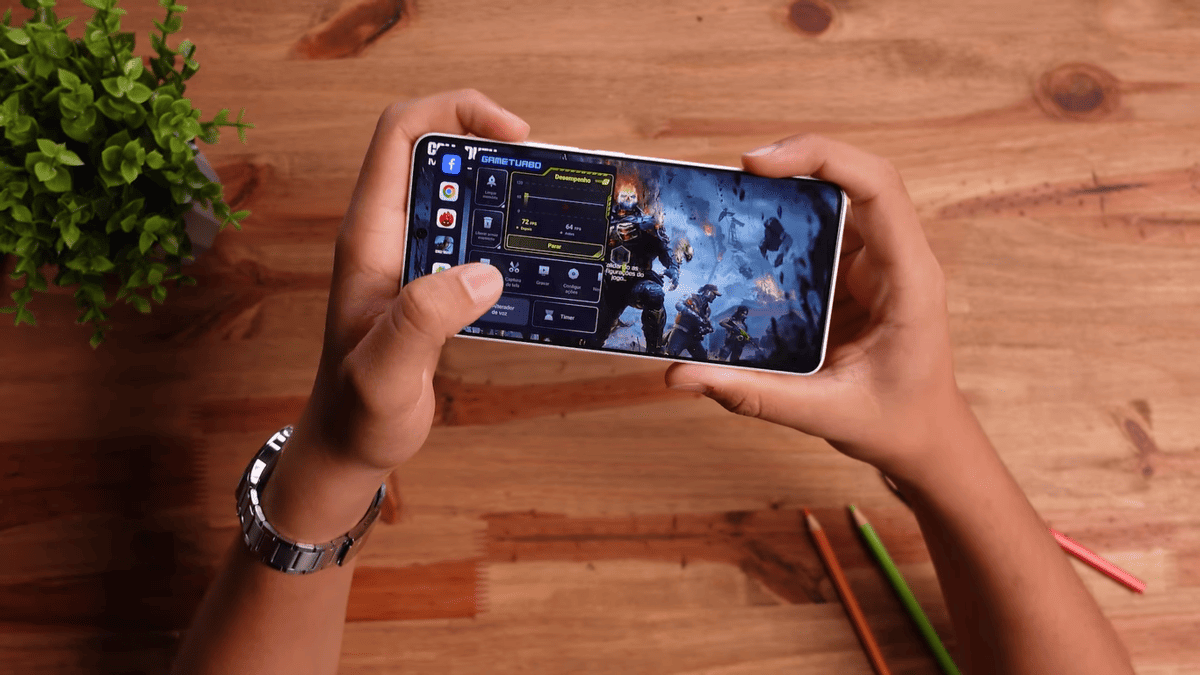 Mãos segurando um celular com a interface do Game Turbo sobreposta a um jogo de ação.