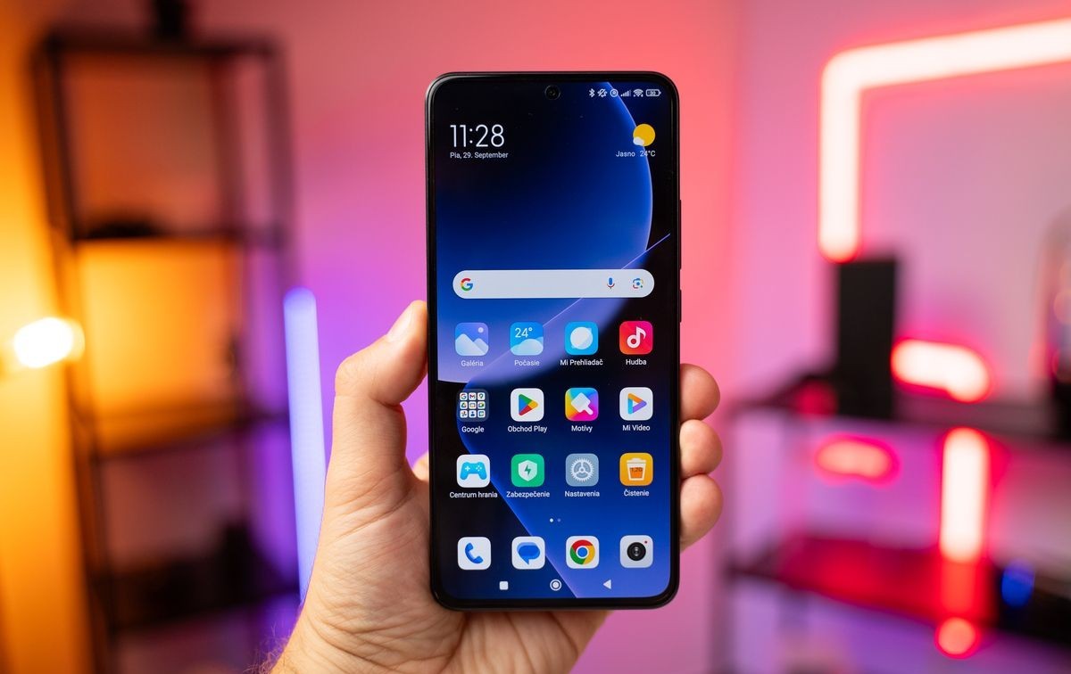 Uma mão segurando um smartphone Xiaomi com a tela inicial mostrando o HyperOS 2.2.