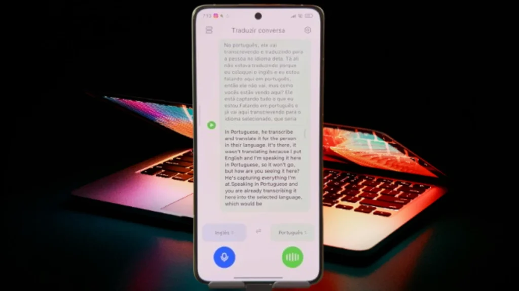 Smartphone exibindo o aplicativo de tradução em tempo real, um dos novos apps do HyperOS 2.2, com um laptop em segundo plano.