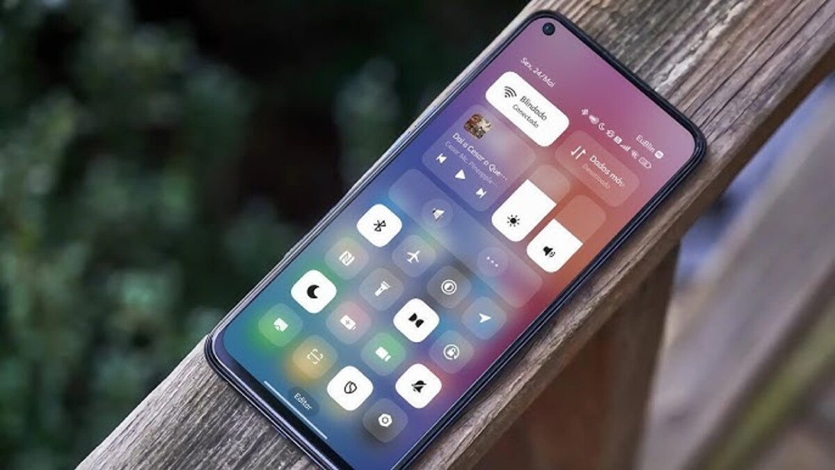 Xiaomi HyperOS 3 pode receber atualizações ao vivo do Android 16 em breve 1 Um smartphone com a interface do usuário do Xiaomi HyperOS 3. A tela mostra o Centro de Controle ou painel de configurações rápidas com botões grandes para Wi-Fi, Bluetooth, modo avião, e outros atalhos. A imagem está com foco na tela do celular e um fundo desfocado.