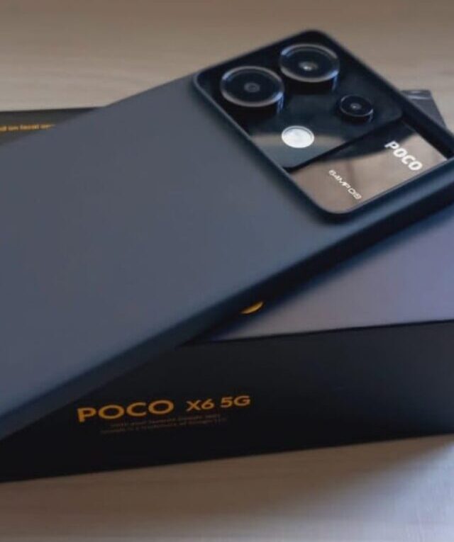 Um smartphone POCO X6 5G preto com uma capa protetora preta, deitado sobre sua caixa original preta e amarela.