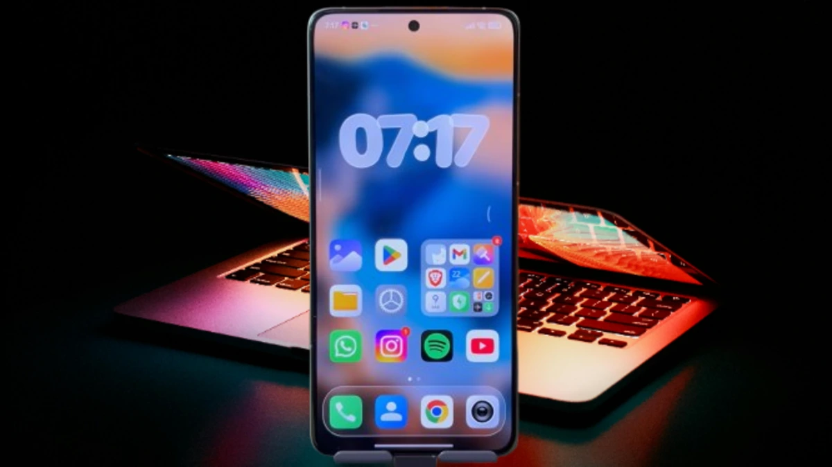 Smartphone com a tela inicial mostrando novos apps do HyperOS 2.2 e um laptop em segundo plano.